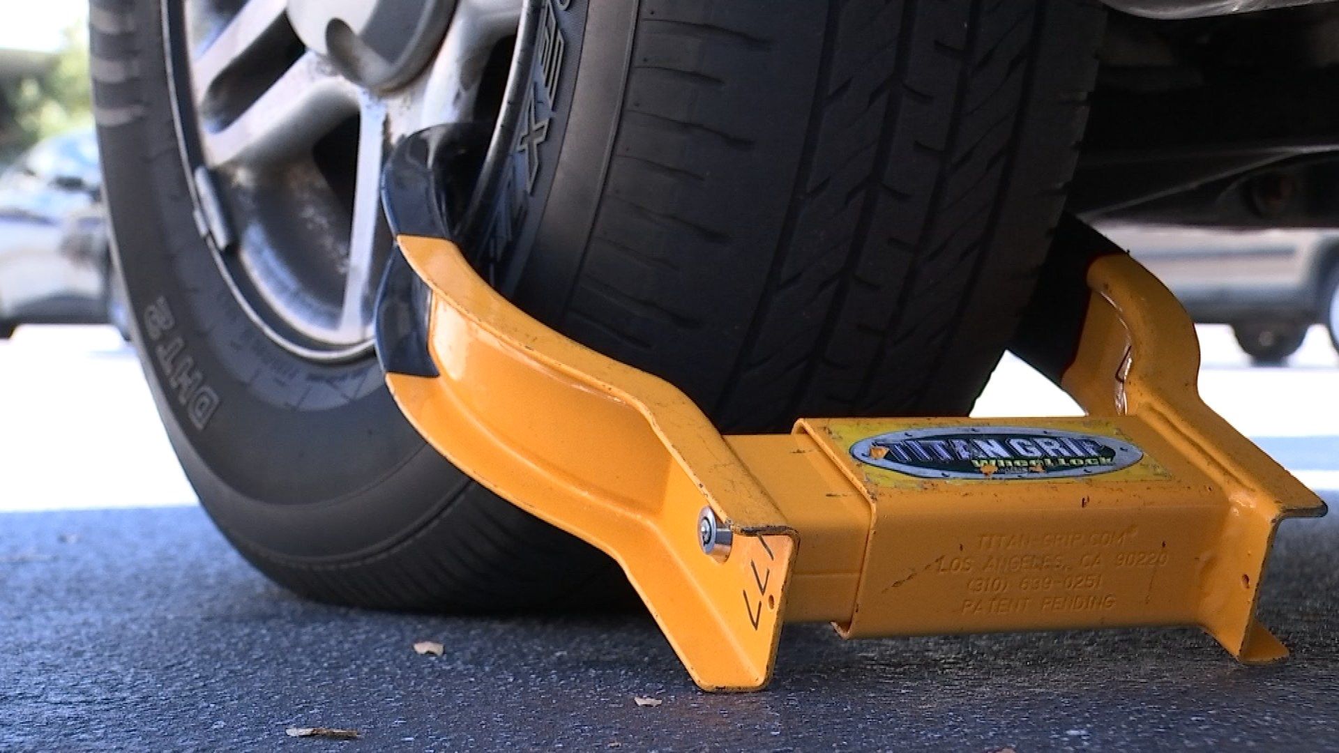 Construction worker uses power tools to cut parking boot off car